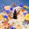 Petal Alchemy bottle on background of lush, colorful flowers and petals